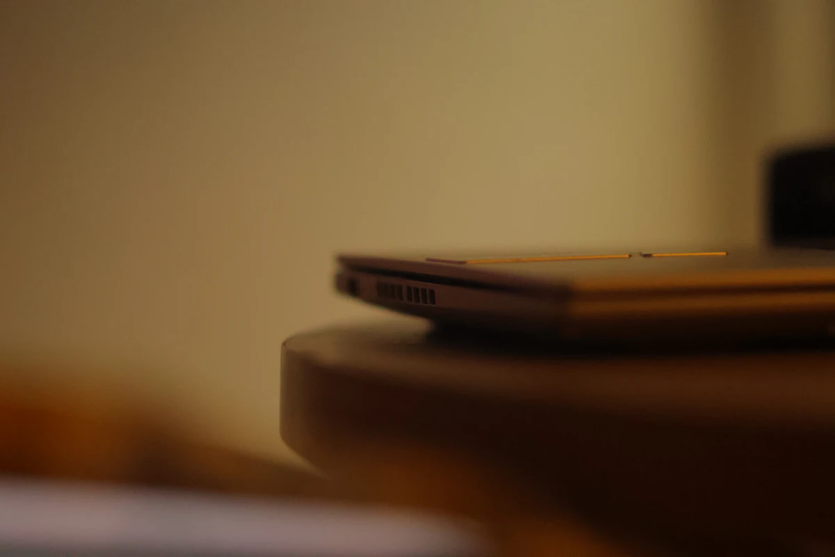 Laptop tertutup tergeletak di meja kayu yang sudah kosong