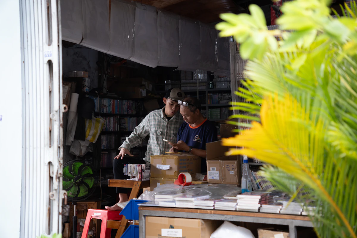 Dua orang bekerja bersama di dalam sebuah toko kecil yang penuh barang
