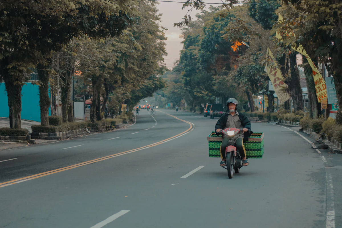 Kurir motor membawa dua kotak paket di jalan