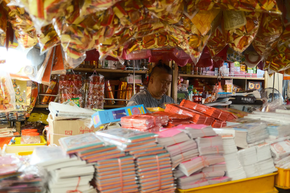 Pemilik toko kelontong berdiri di depan etalase penuh barang dagangan