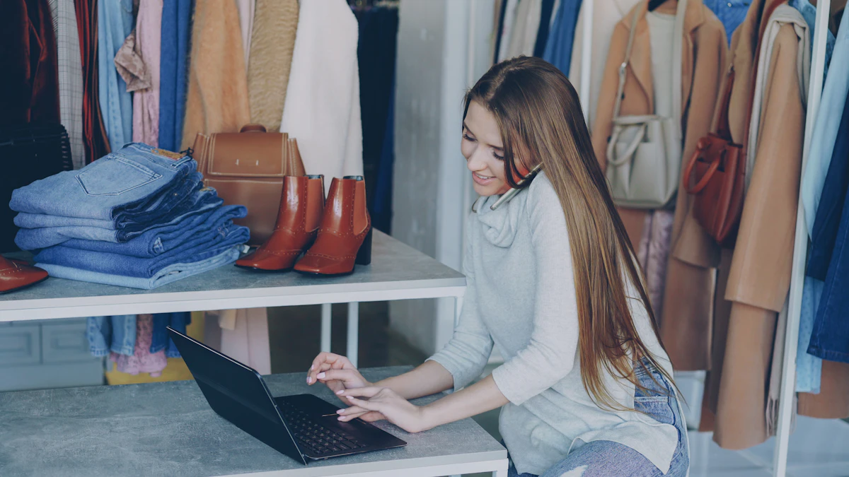 Perempuan bekerja di depan layar sambil dikelilingi tumpukan dan gantungan baju dagangannya