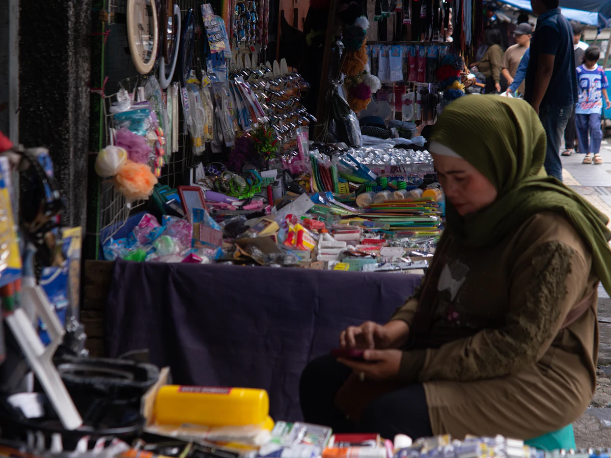 Pedagang perempuan berjilbab melayani pembeli di lapak kecilnya