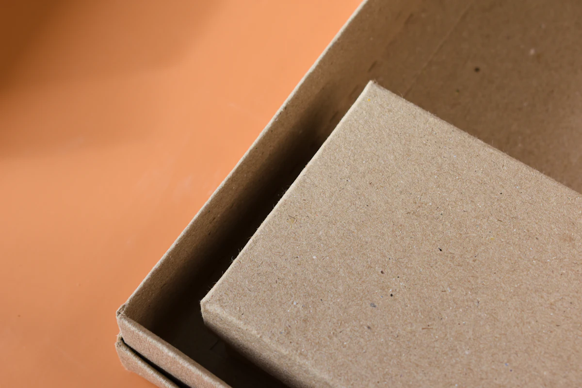 Kardus terbuka berisi bahan pengisi di atas meja packing kayu
