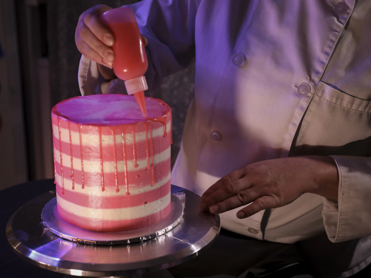 Tangan menghias kue dengan buttercream memakai piping bag di atas meja dapur
