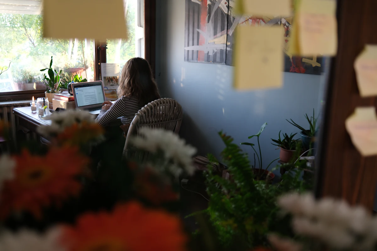 Perempuan bekerja dengan laptop di meja kerja rumah