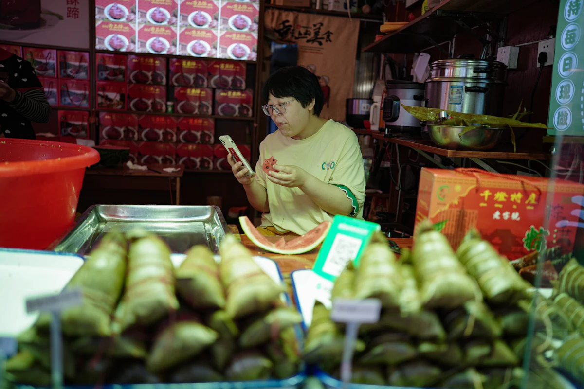 Penjual makanan memeriksa ponsel di antara makanan yang sudah dikemas