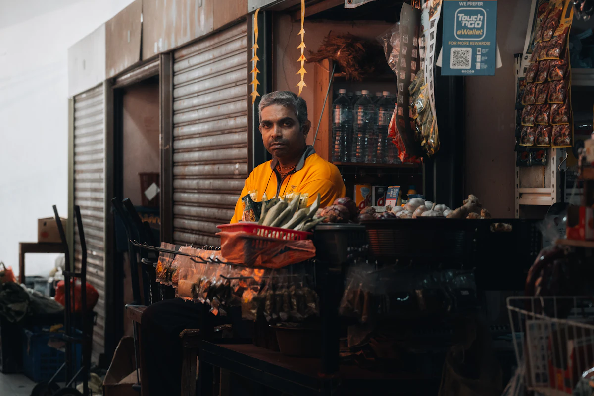 Pemilik toko berdiri di depan tokonya yang penuh barang dagangan